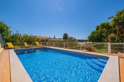 a swimming pool with blue water in a yard at Villa Carela in Albufeira