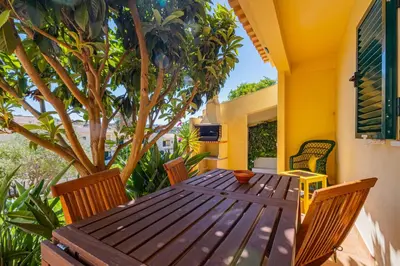 a wooden table and chairs on a patio with a tree at Villa Carela in Albufeira
