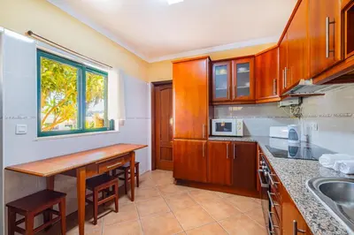 a kitchen with wooden cabinets and a table at Villa Carela in Albufeira