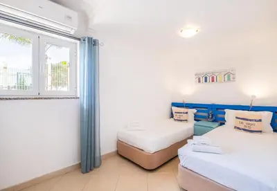 two beds in a room with a window at Margarida Apartment - Ping pong table in Albufeira