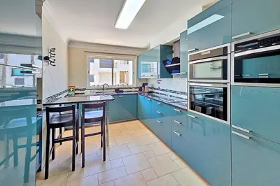 a kitchen with blue cabinets and a counter with stools at Casa Jokpa Mar Near So Rafael Beach in Albufeira