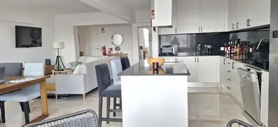 a kitchen with white cabinets and a dining room at Casa Cardoso in Quarteira