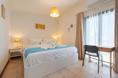 a bedroom with a bed and a desk and a window at Villa Navegante com Piscina Privada em Vilamoura in Quarteira