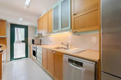 a kitchen with wooden cabinets and a sink and a dishwasher at Villa Navegante com Piscina Privada em Vilamoura in Quarteira