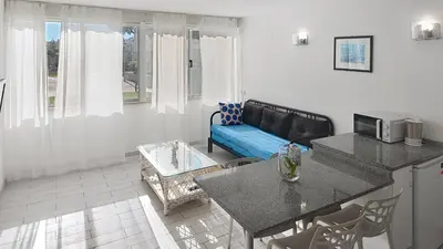 a living room with a blue couch and a kitchen at Vilamar T0 in Vilamoura