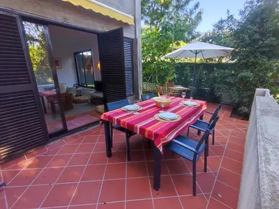 a red table with chairs and an umbrella on a patio at T2 Apartment with private garden in the Balaia Apartments, Albufeira, Algarve in Atalaia
