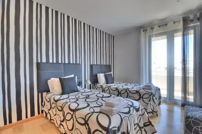 two beds in a room with striped walls at Vilamoura Aquamar in Quarteira