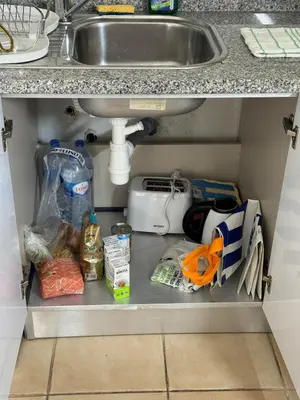 a kitchen cabinet with food under a sink at Relaxing studio in Albufeira Jardim in Albufeira
