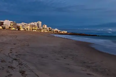 a beach with buildings and the ocean at night at Charming Getaway Apartment in Quarteira in Quarteira