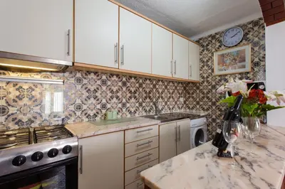 a kitchen with white cabinets and a marble counter top at Apartamento Cardoso in Albufeira