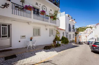 a white building with a table and chairs on a street at Apartamento Cardoso in Albufeira