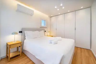 a bedroom with a large white bed and a night stand at Marina Búzios Vilamoura Central 2-Bedroom Apartments in Vilamoura