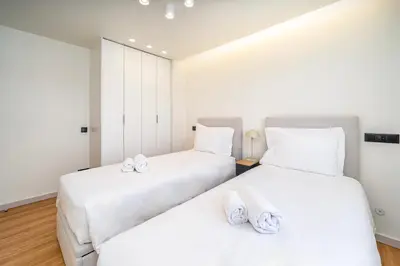 two beds in a room with white walls and wood floors at Marina Búzios Vilamoura Central 2-Bedroom Apartments in Vilamoura