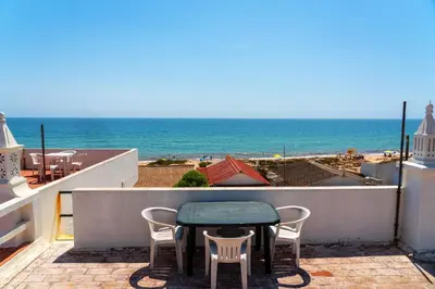 a table and chairs on a balcony with a view of the ocean at Blife Troya private rooms at Faro beach in Faro