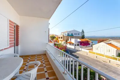 a balcony with a table and chairs and a view of the water at Blife Troya private rooms at Faro beach in Faro