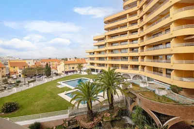 a large apartment building with a swimming pool and palm trees at Marina Mar in Vilamoura