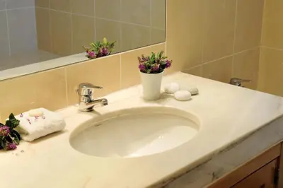 a bathroom sink with a vase of flowers on it at Superior Two Bedroom Apartment in Clube Albufeira in Albufeira