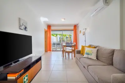 a living room with a couch and a flat screen tv at Bright 2BR with Pool near Beach by LovelyStay in Albufeira