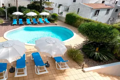 a swimming pool with blue chairs and umbrellas at Sunrise Beach Villa by Delilah Collection in Albufeira