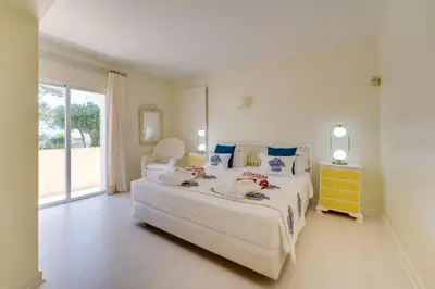 a bedroom with a large white bed and a yellow dresser at Sunrise Beach Villa by Delilah Collection in Albufeira
