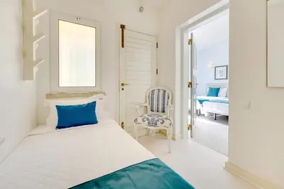 a white bedroom with a bed and a chair at Sunrise Beach Villa by Delilah Collection in Albufeira