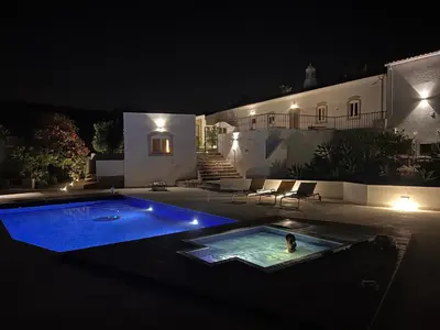 a person swimming in a swimming pool at night at Quinta do Olival - Casa Faro Oeste - Calm & wellness in São Brás de Alportel