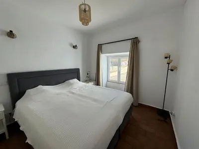 a bedroom with a white bed and a window at Quinta do Olival - Casa Faro Oeste - Calm & wellness in São Brás de Alportel