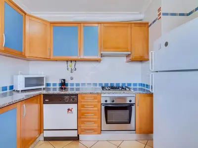 a kitchen with wooden cabinets and a white refrigerator at Colina Beach Holidays, 2 bdr Apartment Quarteira in Quarteira
