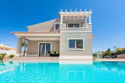 a villa with a swimming pool in front of a house at Villa Gale Coast in Guia