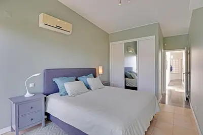 a bedroom with a large bed with blue pillows at Terras Novas Albufeira in Albufeira