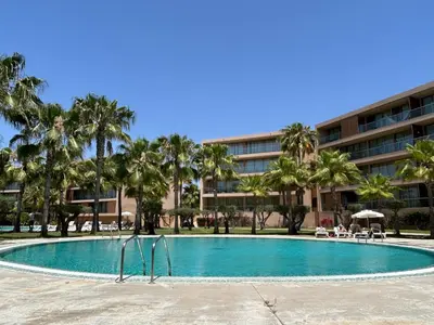 a swimming pool with palm trees in front of a building at Vila das Lagoas 9A 3D in Guia