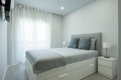 a white bedroom with a bed and a window at Casa Pereira - Guest House Faro City Center in Faro