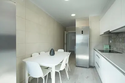 a white kitchen with a white table and white chairs at Casa Pereira - Guest House Faro City Center in Faro