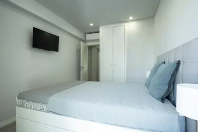 a white bedroom with a bed and a television at Casa Pereira - Guest House Faro City Center in Faro