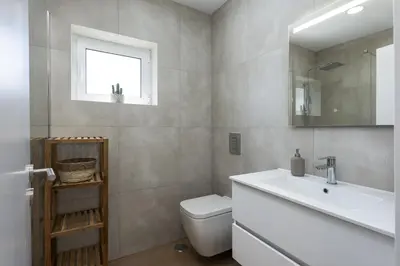 a bathroom with a sink and a toilet and a mirror at Alva - cozy apartment with pool by HD in Vilamoura