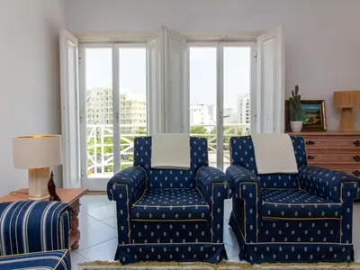 a living room with two blue chairs and a window at Vilamoura Sea View Apartment by Stay ici Algarve Holiday Rental in Quarteira