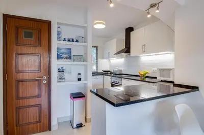 a kitchen with white cabinets and a wooden door at Relaxing 2BD Apt 500m Beach w AC WiFi Pool in Albufeira