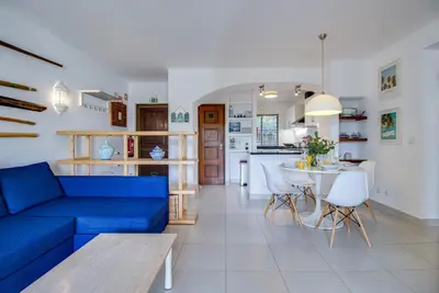a living room with a blue couch and a kitchen at Relaxing 2BD Apt 500m Beach w AC WiFi Pool in Albufeira