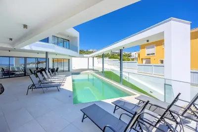 a patio with chairs and a swimming pool on a building at Villa Vista Albufeira Sea Views Heated Pool Walk To Marina in Albufeira