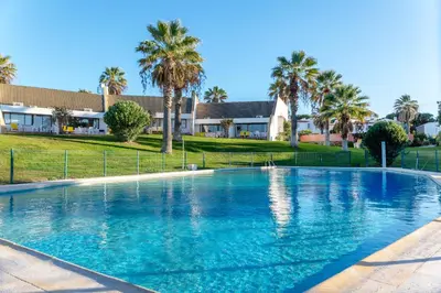 a large swimming pool with palm trees and houses at Villa Lina - Vilamoura in Quarteira