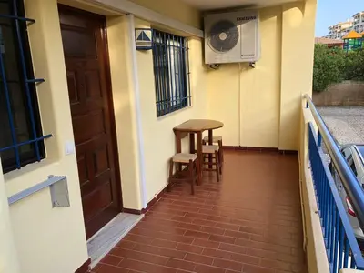 a balcony with a table and chairs and a door at Beautiful T2 Apartamento Olhos do Mar in Olhos de Água