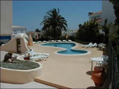 a swimming pool with white chairs and a resort at Beautiful T2 Apartamento Olhos do Mar in Olhos de Água