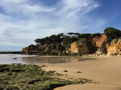 a beach with a house on top of a mountain at Beautiful T2 Apartamento Olhos do Mar in Olhos de Água