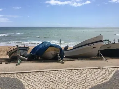 two boats on a beach with the ocean in the background at Beautiful T2 Apartamento Olhos do Mar in Olhos de Água
