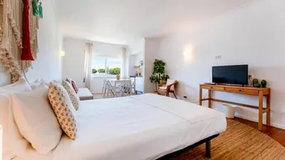 a bedroom with a white bed and a television at Studio 54 by Sunnyway in Albufeira