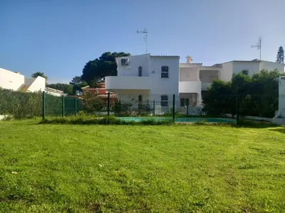 a fence in front of a house with a grass field at Vilamoura Pinhal Golf Course in Quarteira