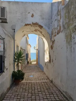 an alley with an archway in a town with the ocean at Casa da Porta da Praia - 3 Bedroom Castle Wall House in Albufeira