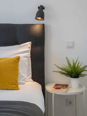 a bed with a yellow pillow and a plant on a table at Casa da Porta da Praia - 3 Bedroom Castle Wall House in Albufeira