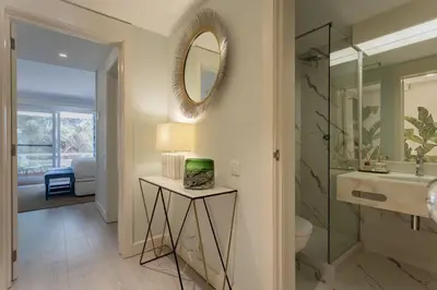 a hallway with a table with a lamp and a mirror at The Palm Nest