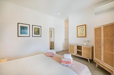 a white bedroom with a bed and a cabinet at Casa Joaninha - Heated pool - Algarve in Algoz